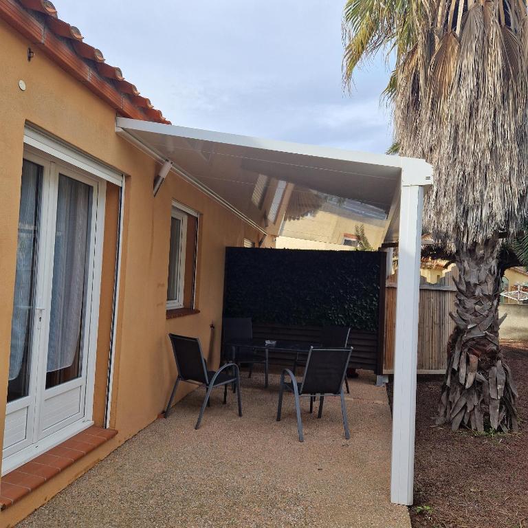 une terrasse avec une table et des chaises sous un parasol dans l'établissement rêve méditerranéen, Maison de rêve, au Barcarès