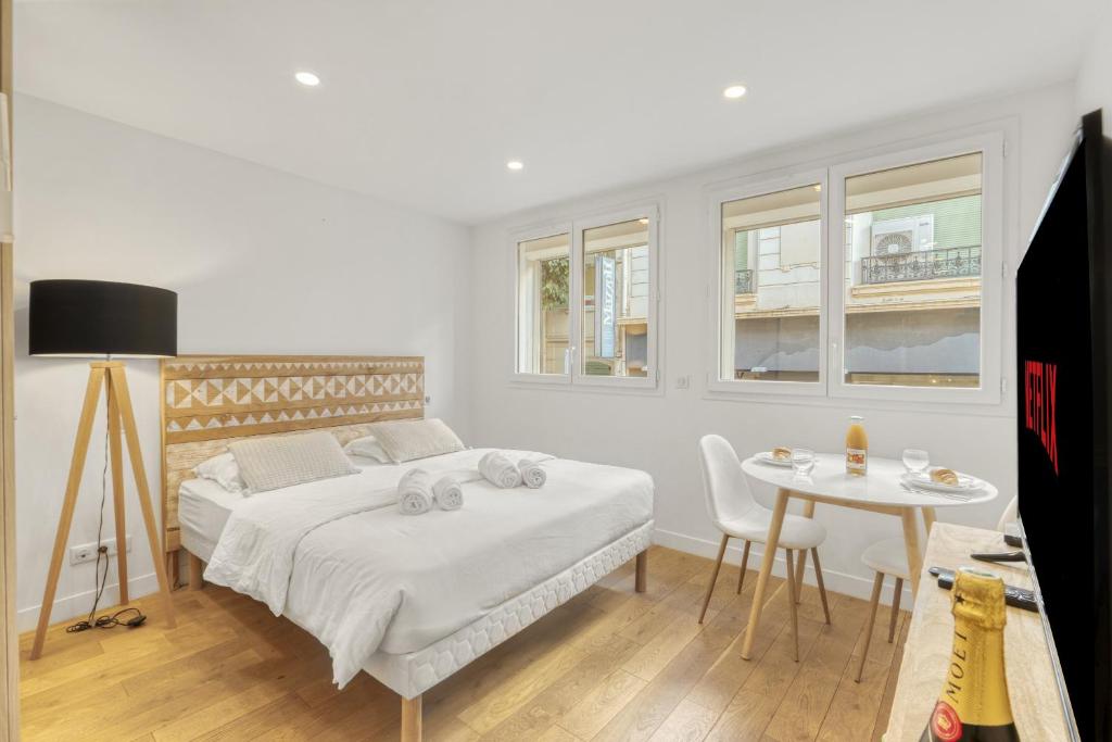 une chambre blanche avec un lit et une table dans l'établissement Magnifique studio Macé, à Cannes