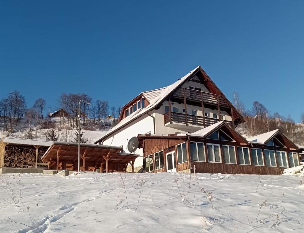 een groot houten huis in de sneeuw met sneeuw bij The Viewpoint in Măgura