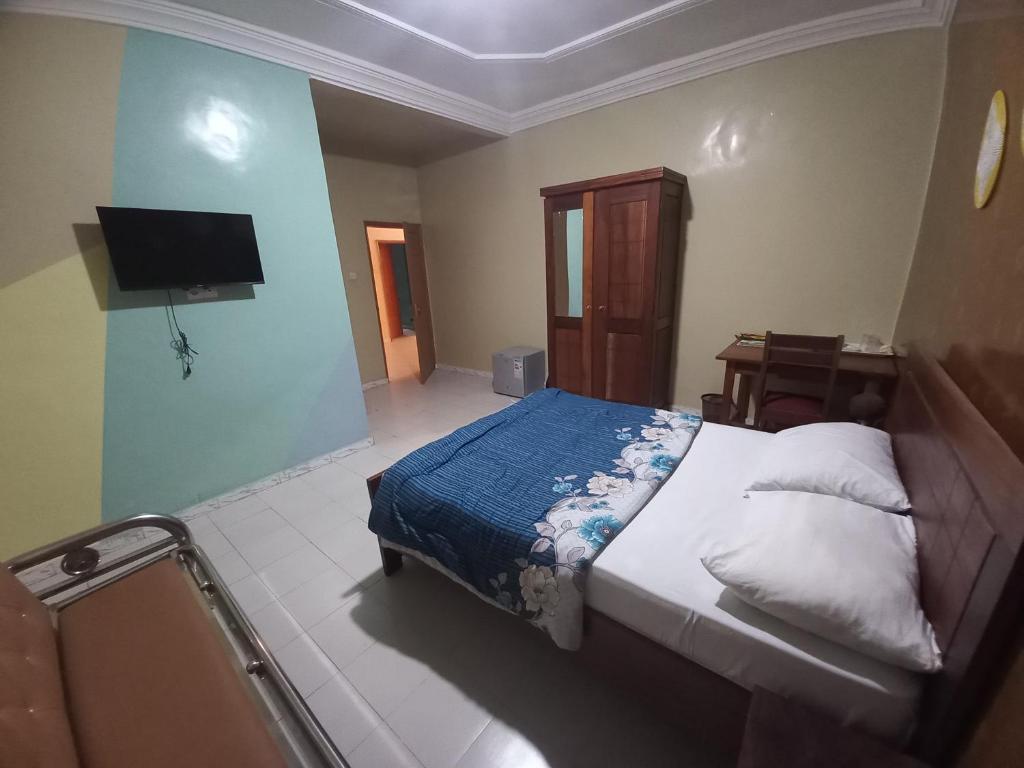 a bedroom with a bed and a flat screen tv at SAM RESIDENCE Jàmm ak Cofeel in Saint-Louis
