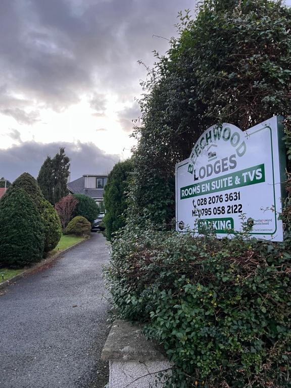 a sign for a house on the side of a bush at Beechwood Lodges in Ballycastle