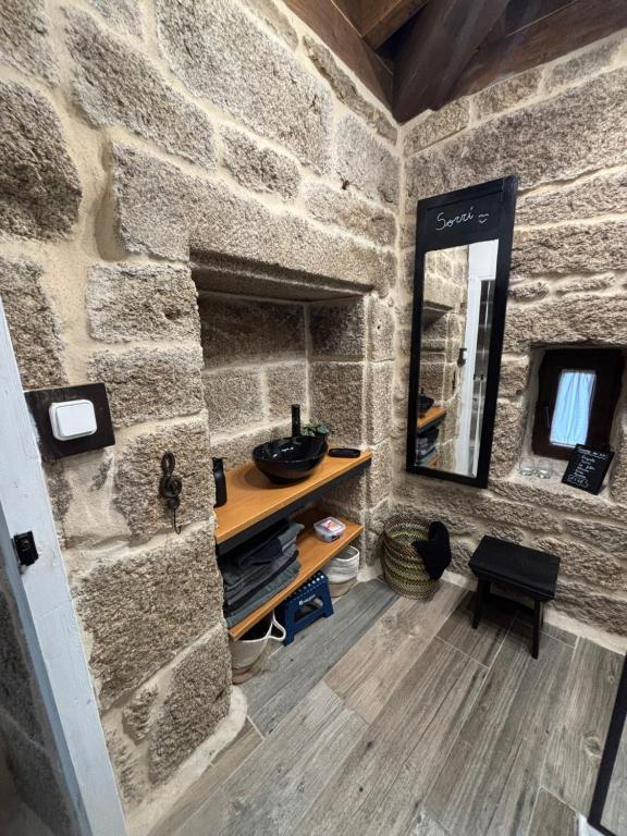 y baño con pared de piedra, tocador y espejo. en Aturuxo VUT OR 994, en Trasmiras