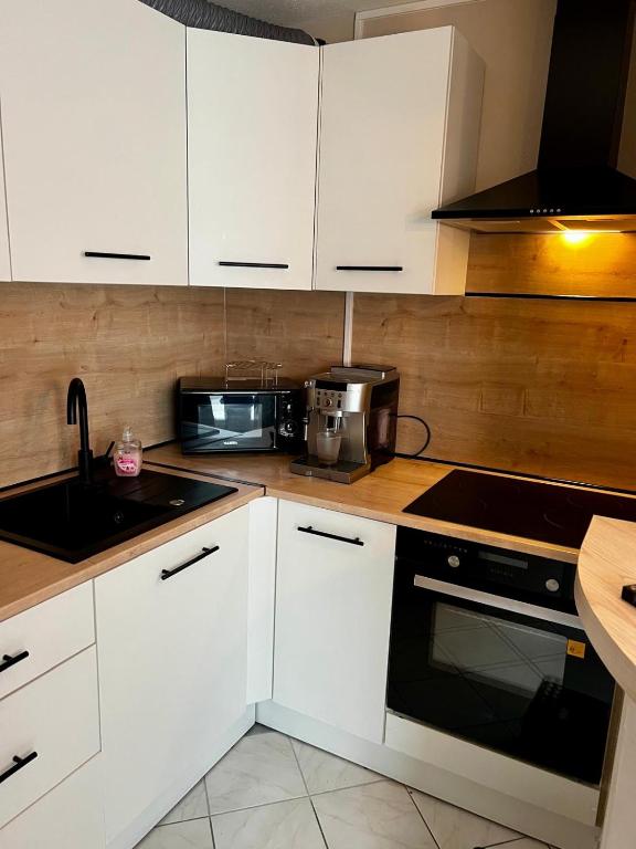 La cuisine est équipée de placards blancs et d'un four avec plaques de cuisson noires. dans l'établissement Appartement Calme, à Morsbach