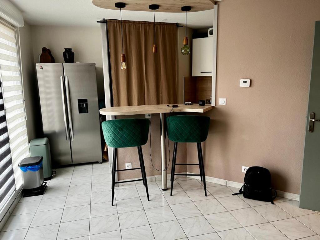 a kitchen with a counter with two stools and a refrigerator at Appartement Calme in Morsbach