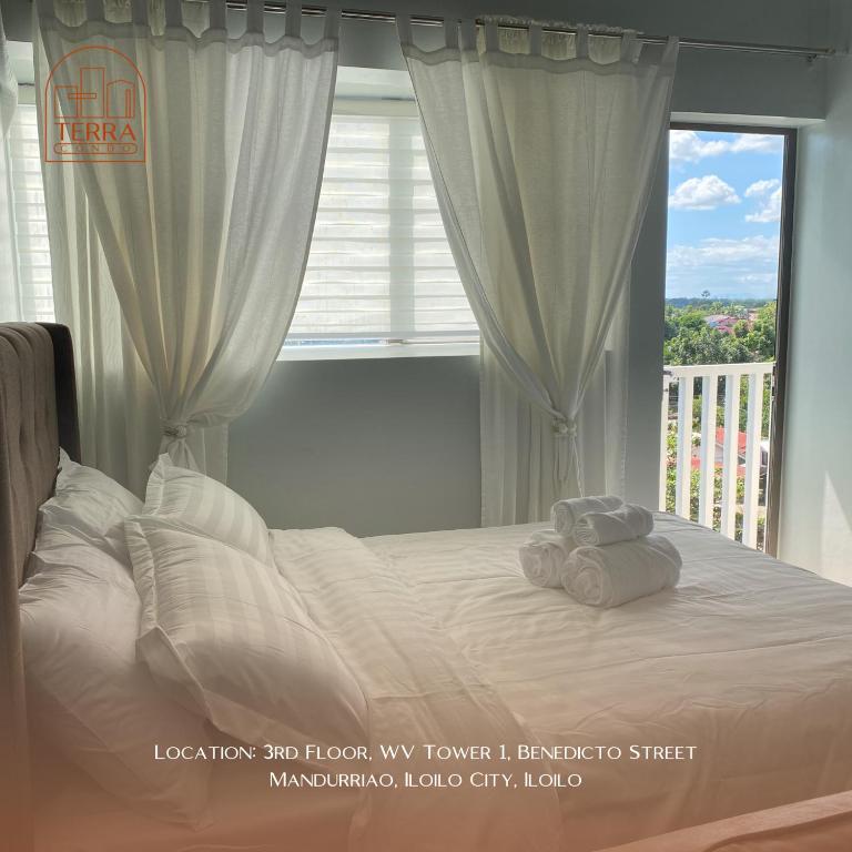 una camera da letto con un letto con lenzuola bianche e una finestra di Terra Condo a Città di Iloilo