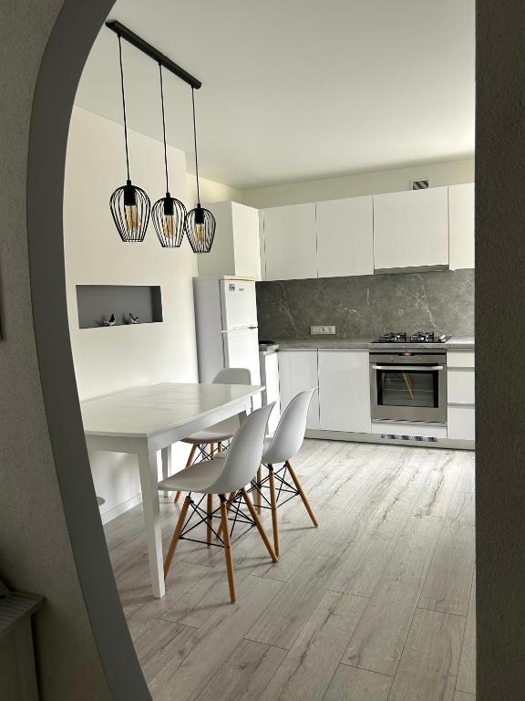 a white kitchen with a white table and chairs at Vivist apartments in Druskininkai