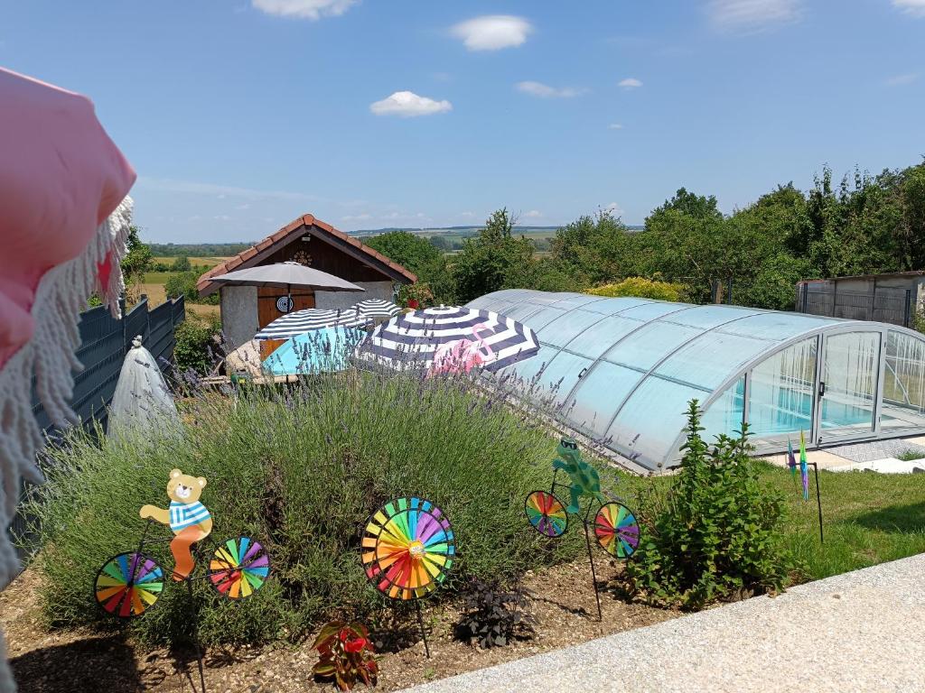 a garden with a greenhouse and colorful pinwheels at Chambres d'hôtes piscine couverte & chauffée in Bouquemont