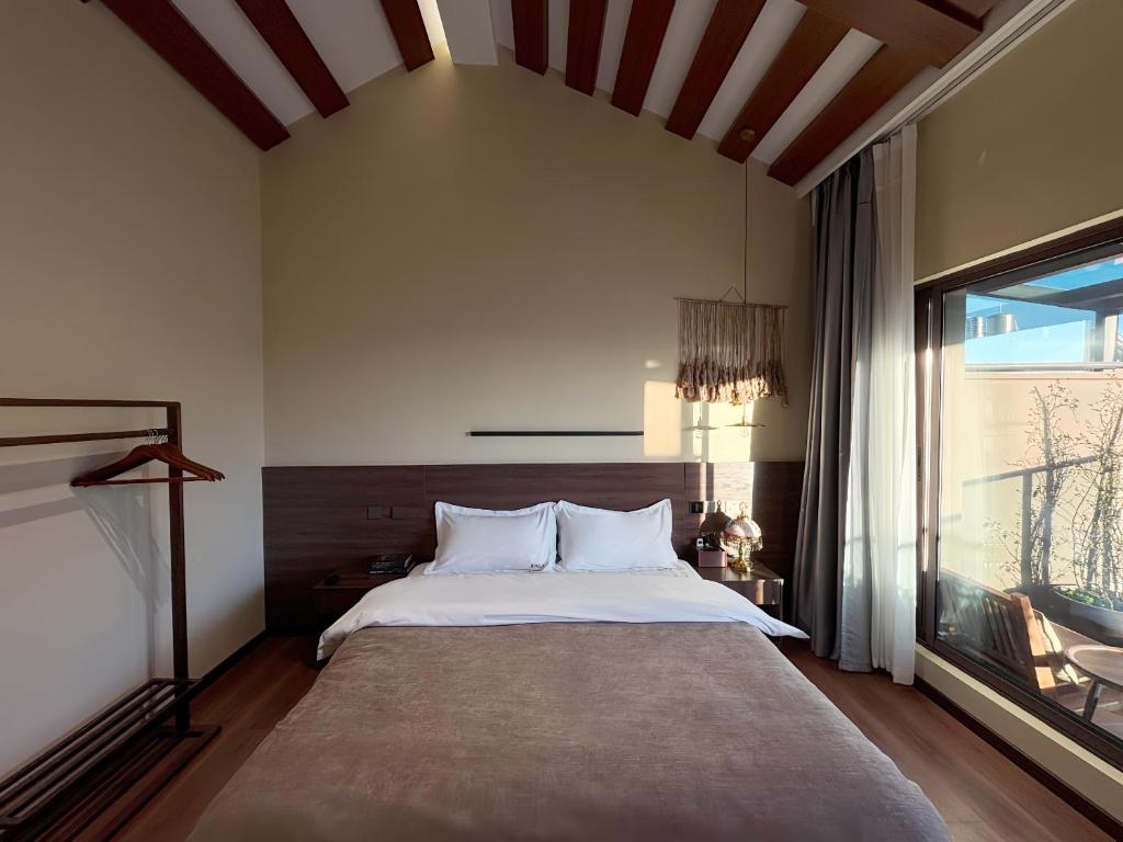 Un dormitorio con una cama grande y una ventana grande. en Luyu Shijian B&B, en Lijiang
