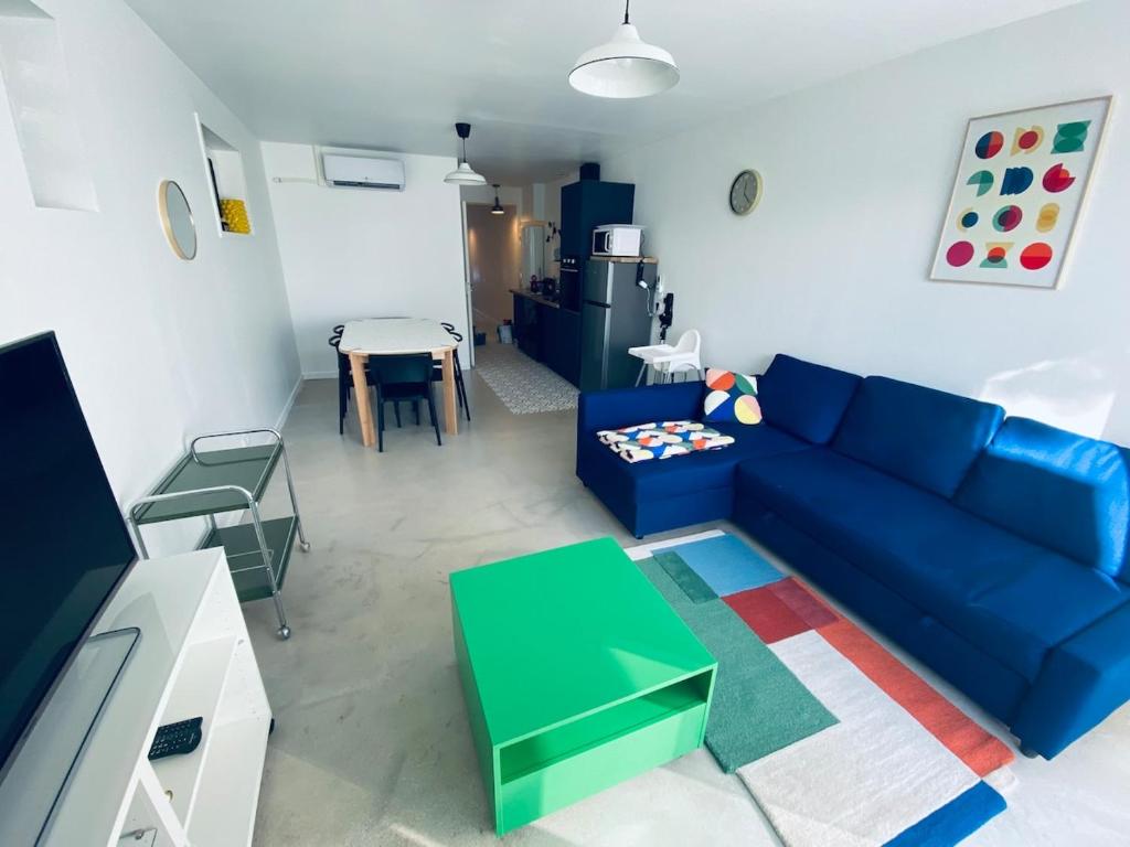 un salon avec un canapé bleu et une table dans l'établissement Charmante petite maison, à Hourtin