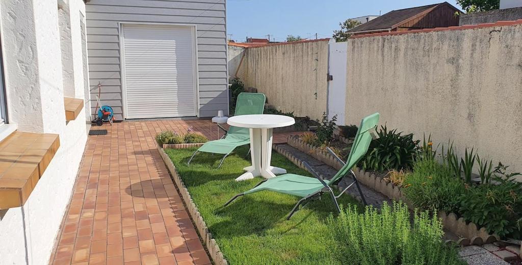 d'une terrasse avec 2 chaises et une table sur gazon. dans l'établissement Jolie Maison de Vacances, à Les Sables-dʼOlonne