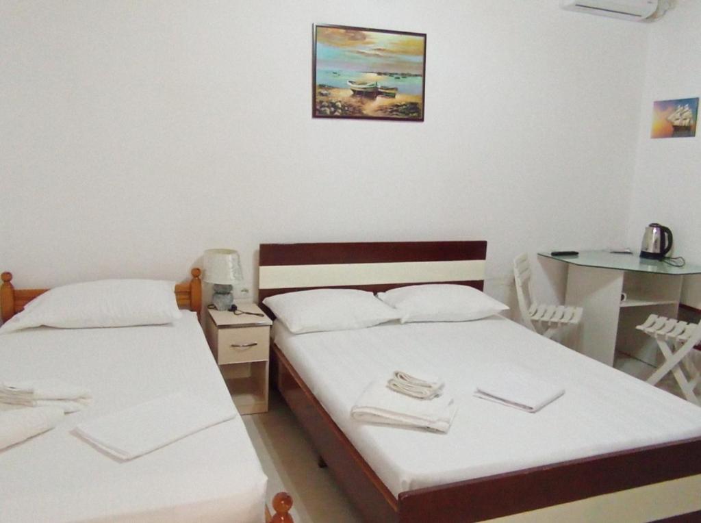 two beds in a room with a desk and a table at Dona's Room in Sarandë