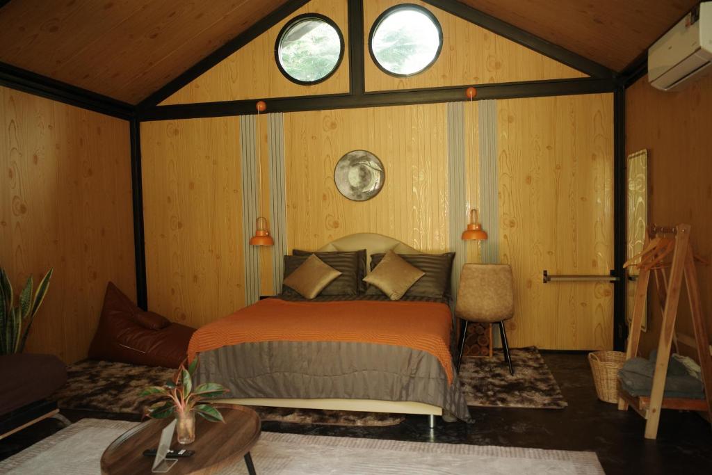 ein Schlafzimmer mit einem Bett in einem Zimmer mit zwei Fenstern in der Unterkunft Baanraisongshul K&E Gardens in Khlong Lan