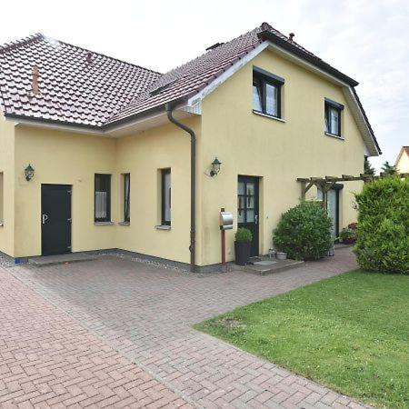 a large yellow house with a brick driveway at Ferienwohnung Klast F51 in Kühlungsborn