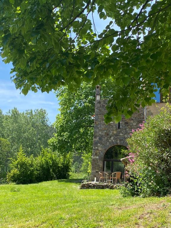 un bâtiment en pierre avec une table et des chaises dans un champ dans l'établissement Gîte Azalée, à Les Brousses