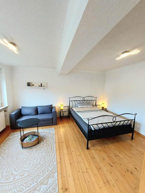 a bedroom with a bed and a couch at Gemütliche Ferienwohnung auf Hof Santangelo in Dickesbach