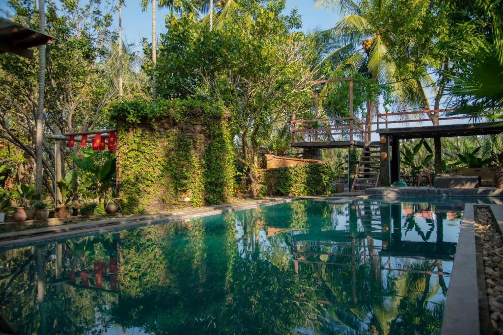 a swimming pool in a resort with trees at Laoxao RiverStone Villa in Hoi An