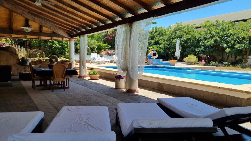 a patio with lounge chairs and a swimming pool at B&B Il Resort Dell'Artista in Venetico