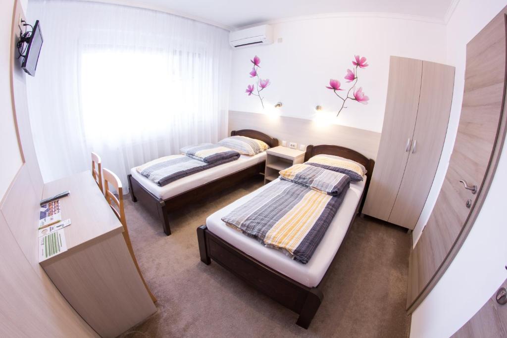 um pequeno quarto com 2 camas e uma janela em Vándor Vendégház em Szeged