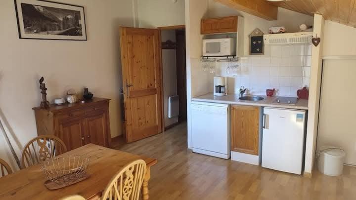 - une cuisine avec des appareils blancs et une table en bois dans l'établissement Studio Résidence grand tetras, à Samoëns