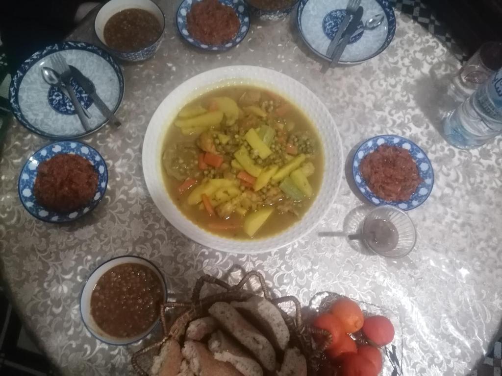 a table topped with a bowl of soup and some food at Dar lmallouki in Meknès