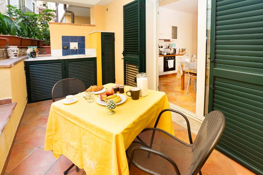 a table with a yellow table cloth and chairs in a kitchen at Le Tartarughe Aparthotel in Letojanni