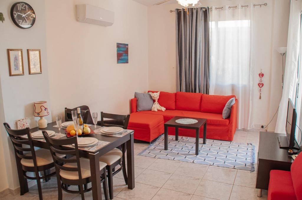 a living room with a red couch and a table at Cozy 1 bedroom apartment in walking distance to the municipal beach in Paphos City