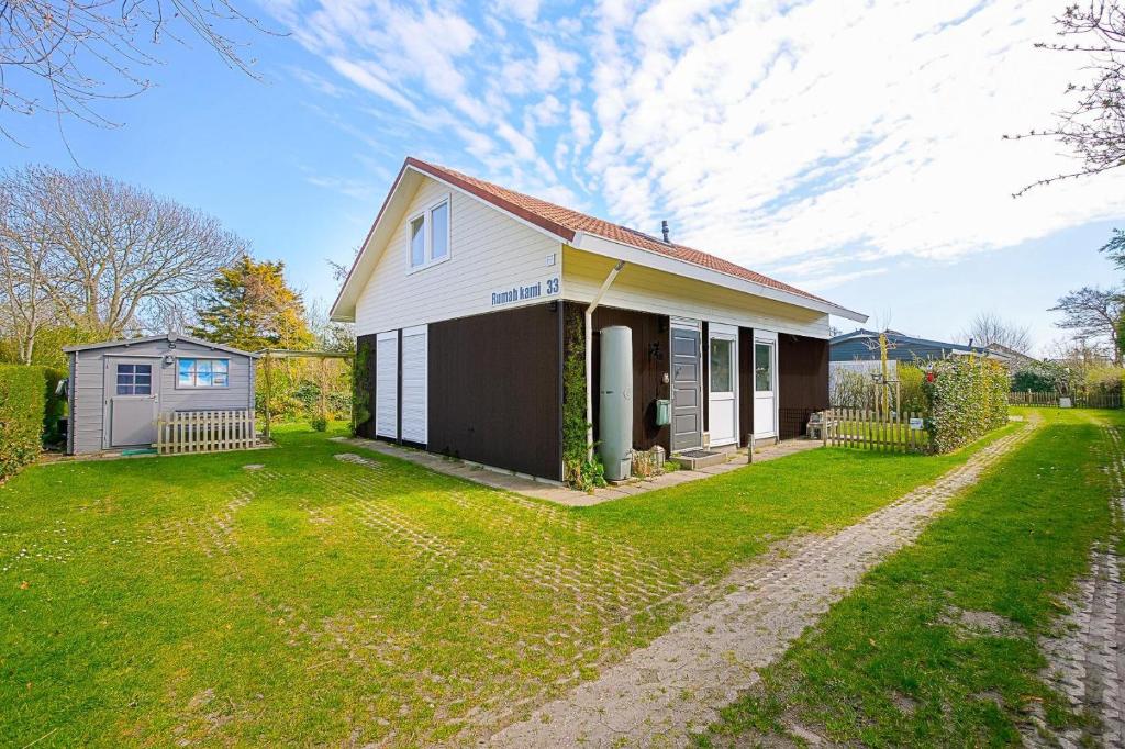 una pequeña casa blanca con patio en Vakantiehuis Rumah Kami - Julianadorp aan Zee, en Julianadorp