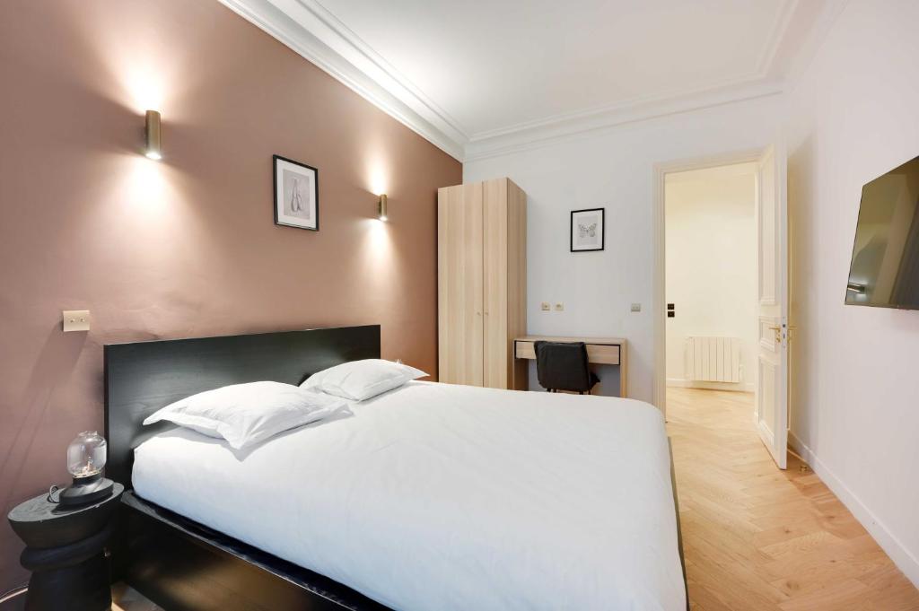une chambre avec un lit blanc et un bureau dans l'établissement Spacious apartment - 3BR-8P - Ternes, à Paris