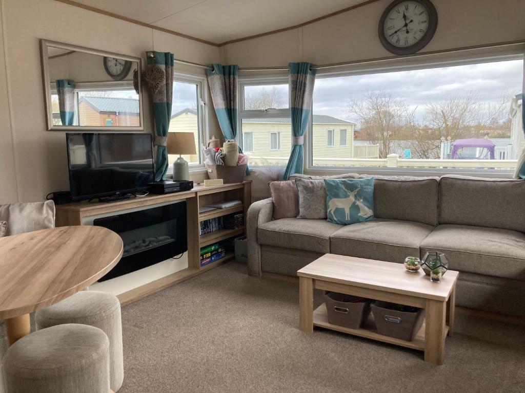 ein Wohnzimmer mit einer Couch, einem Fernseher und einem Tisch in der Unterkunft Tattershall Lakes Luxury Hot Tub Breaks in Tattershall