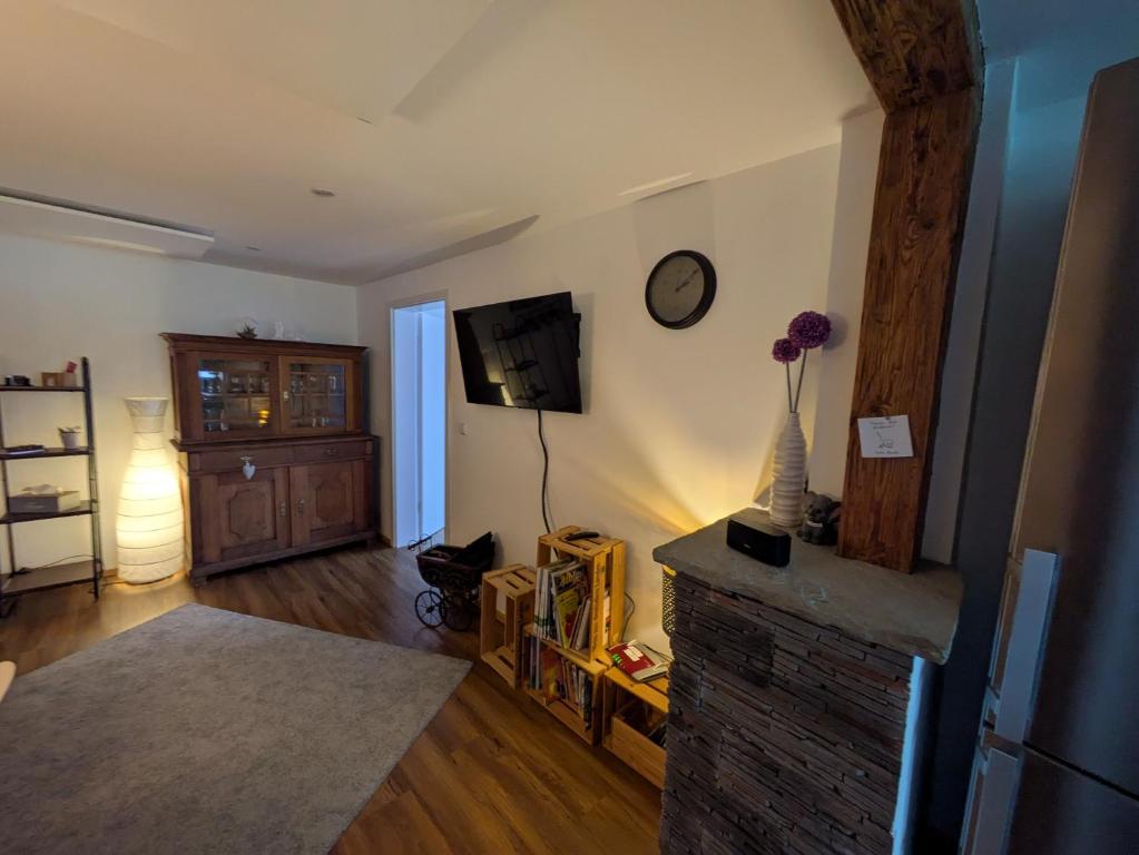 a living room with a fireplace and a clock on the wall at fewoflagmeier Meidelstetten I Maisonetten Wohnung Alb in Hohenstein