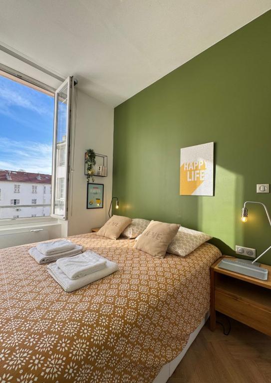 une chambre avec un grand lit et une grande fenêtre dans l'établissement Cosy Cocoon Place Massena, à Nice