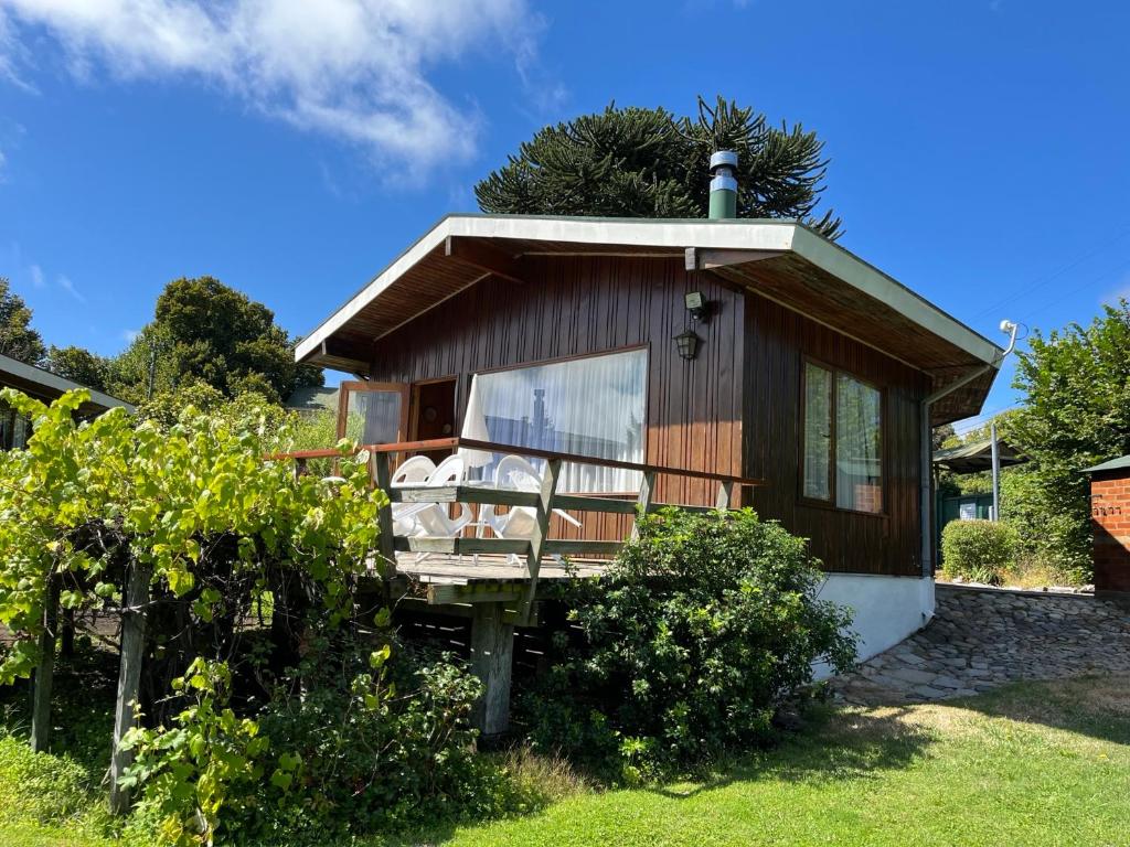 Cabañas Los Tilos Pucón في بوكون: كابينة صغيرة مع شرفة في الفناء