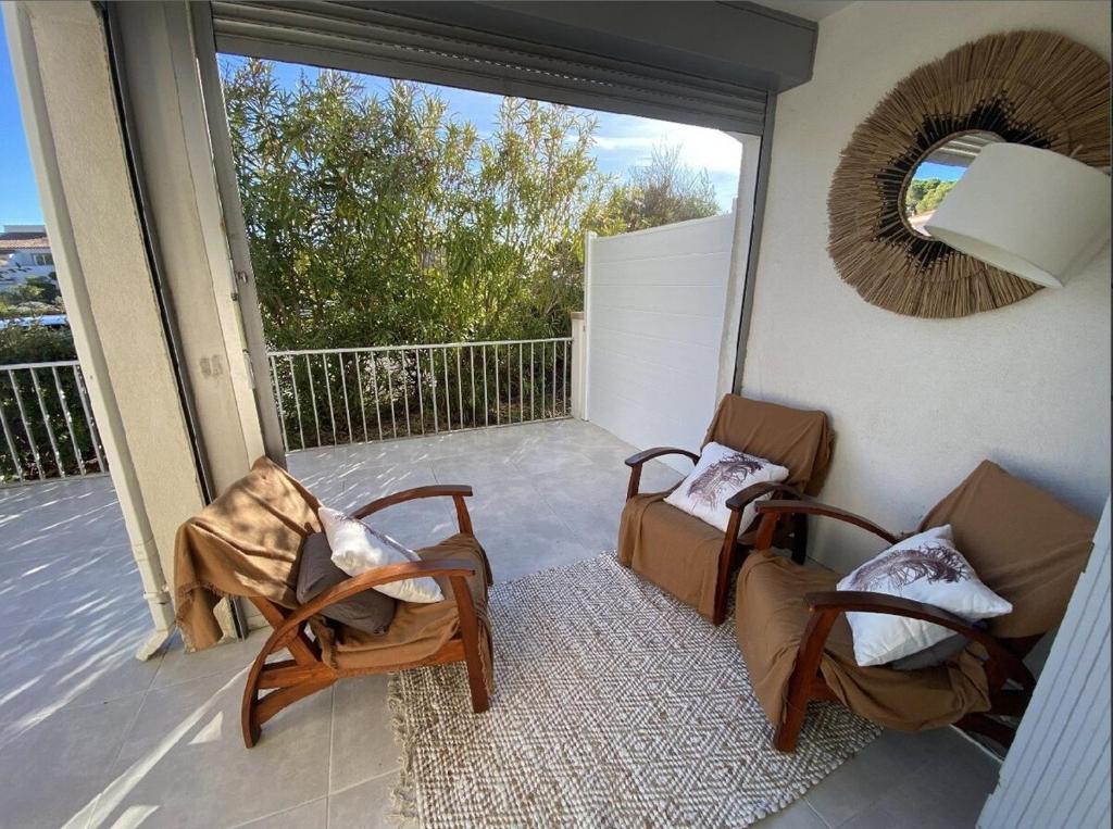 un balcon avec deux chaises et une grande fenêtre dans l'établissement Appartement climatisé en rez-de-chaussée 3 personnes max, au Cap d'Agde