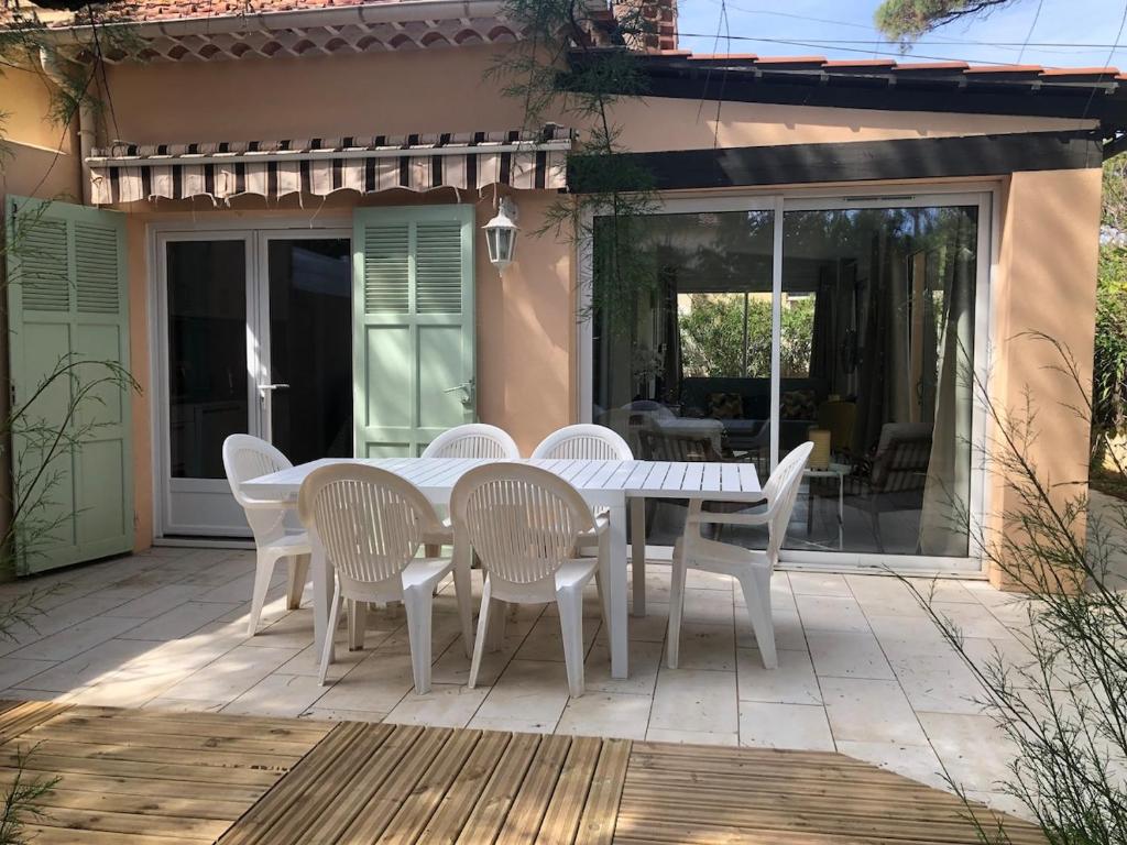 une table blanche et des chaises sur une terrasse dans l'établissement Maison bord de mer climatisée La Capte , Hyères, à Hyères