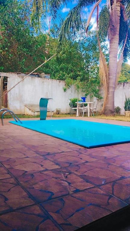 una piscina azul con una mesa y palmeras en Casa Mari, en São Gabriel
