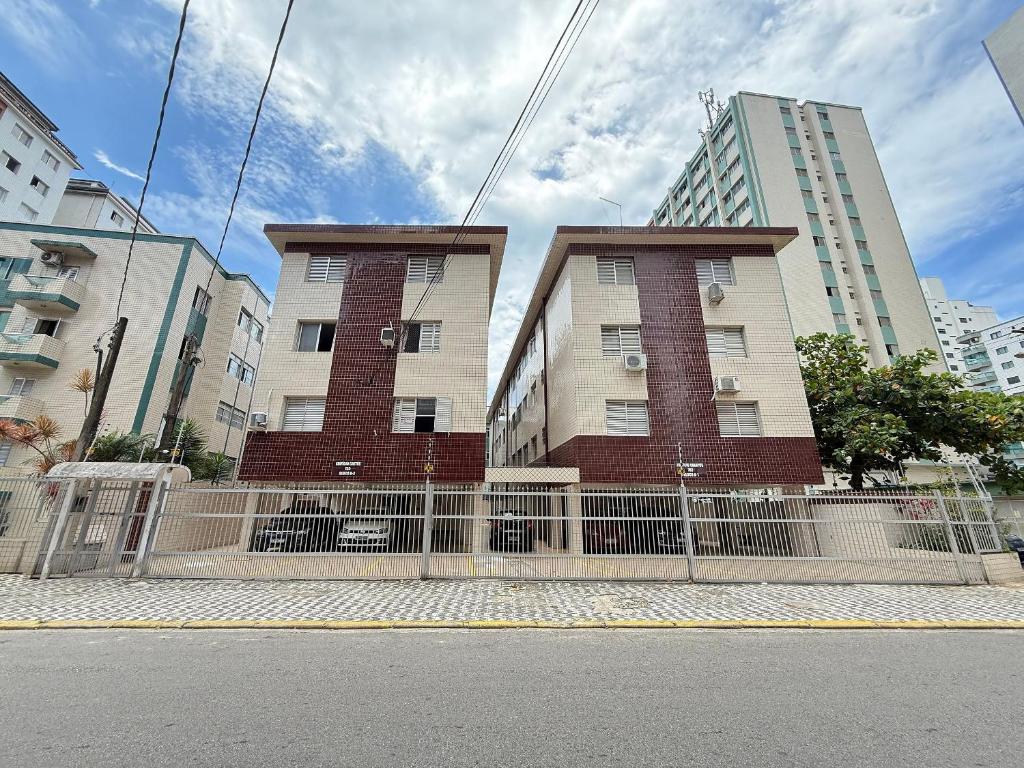 un edificio con una valla delante de algunos edificios en Pie en la arena de la playa Tupi, en Samaritá