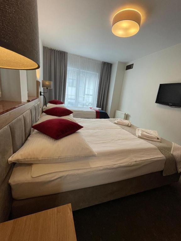 a hotel room with three beds with red pillows at Villa Roma przy wyciągu na Szrenicę in Szklarska Poręba