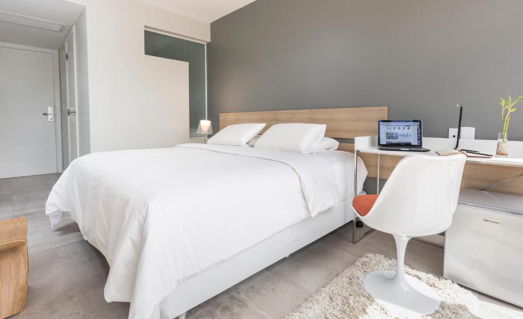 a bedroom with a white bed and a desk with a computer at Hub Hotel Asuncion in Asuncion
