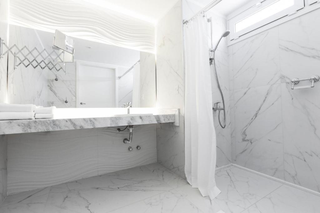 a white bathroom with a shower and a sink at Hub Hotel Asuncion in Asuncion
