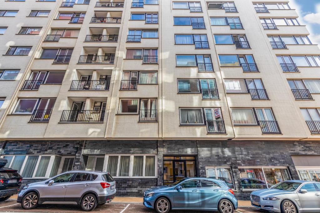 two cars parked in front of a tall building at Residentie Strand in Blankenberge