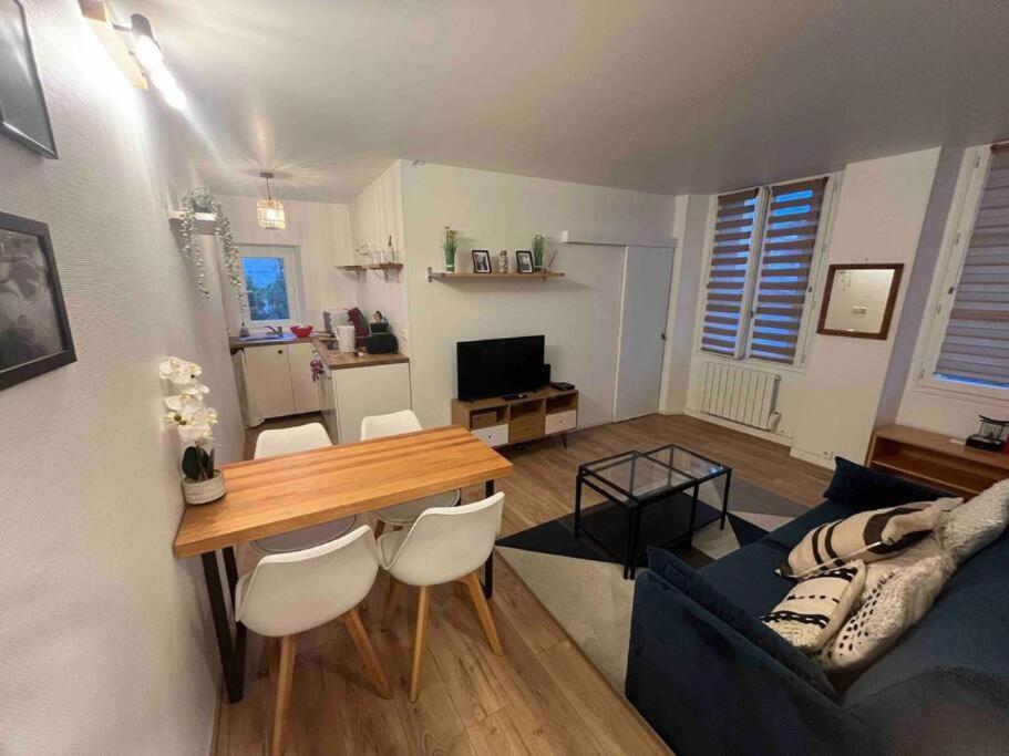 un salon avec une table et un canapé bleu dans l'établissement Appartement cosy, 10 min Château Versailles et 5 min Gare, à Versailles