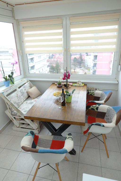 a dining room with a wooden table and two windows at Nensica in Vukovar
