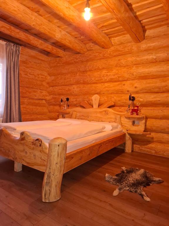 Un dormitorio con una cama en una cabaña de troncos en Chalet Gabriela, en Şarul Dornei
