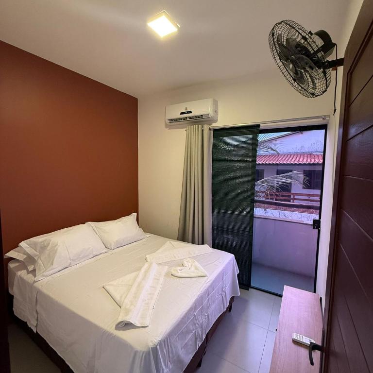 a bedroom with a white bed with a window at Triplex Flecheiras in Flecheiras