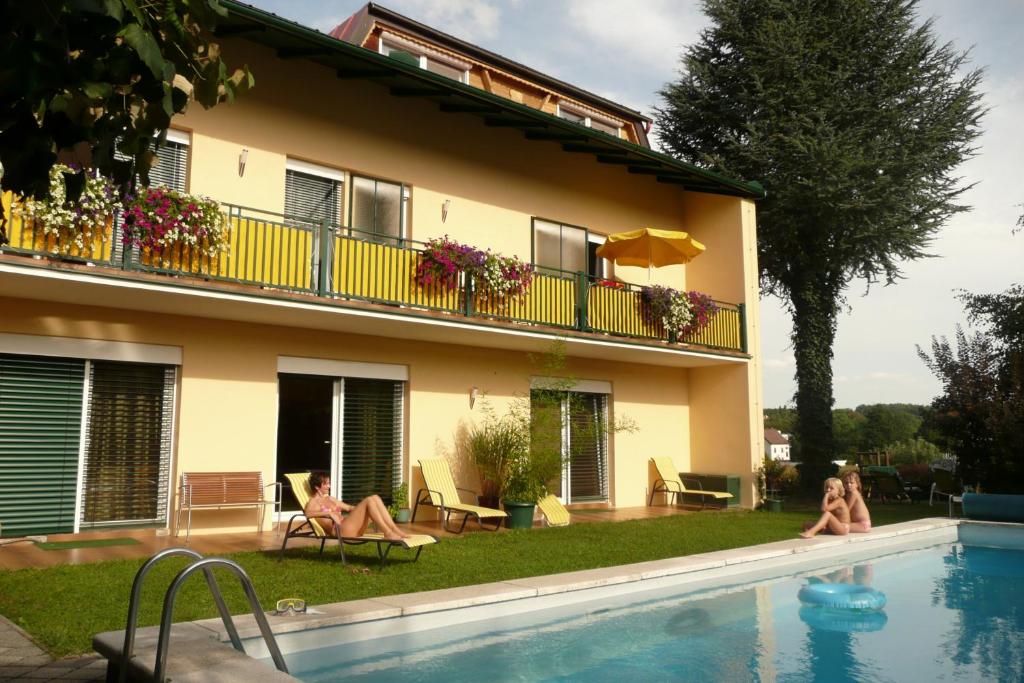 two women sitting in a swimming pool next to a building at Landhaus Pension Jany in Bad Tatzmannsdorf