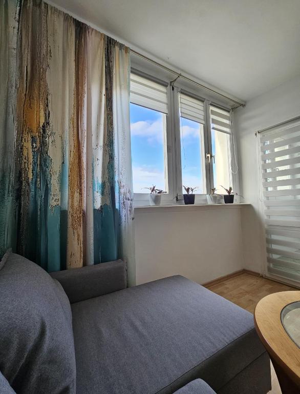 a living room with a couch and two windows at Apartament WELES in Bolesławiec