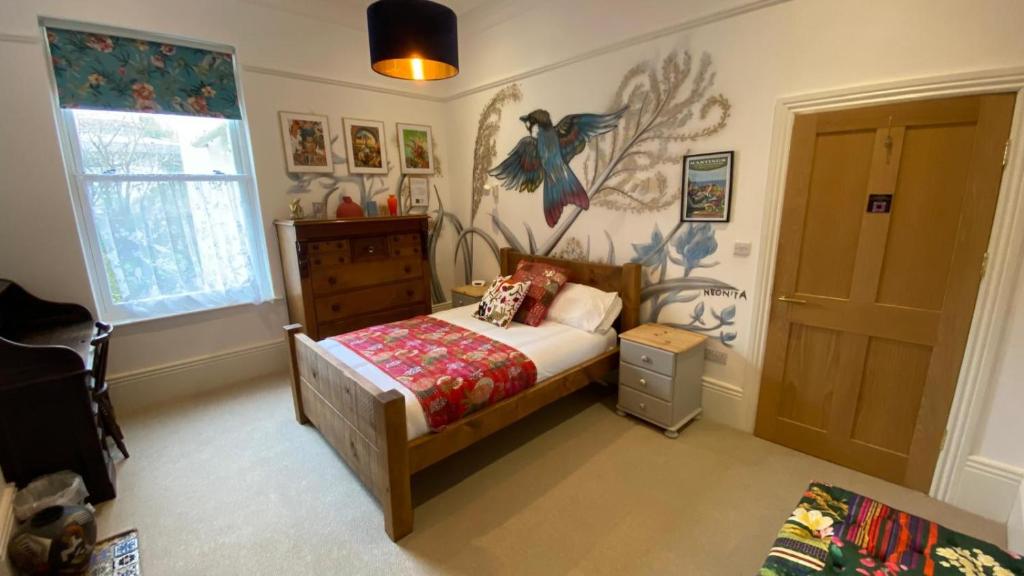 a bedroom with a bed and a wall with a bird mural at Church Retreat - A Magnificent Seaside Apartment-Award Winning in Hastings