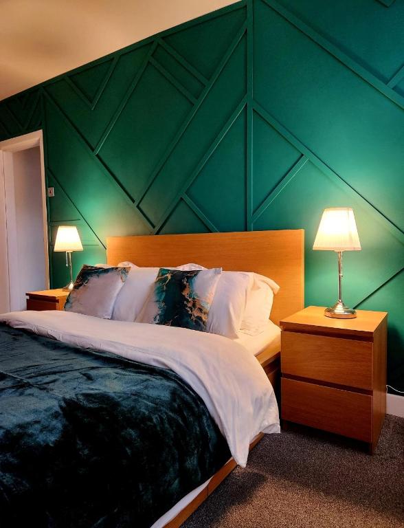 a bedroom with a green wall with a large bed at Modern Spacious Apartment Steps from City Centre in Norwich