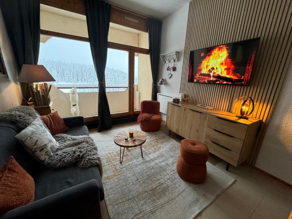 un salon avec un canapé et une télévision avec un feu dessus dans l'établissement La belle échappée, à Prénatier