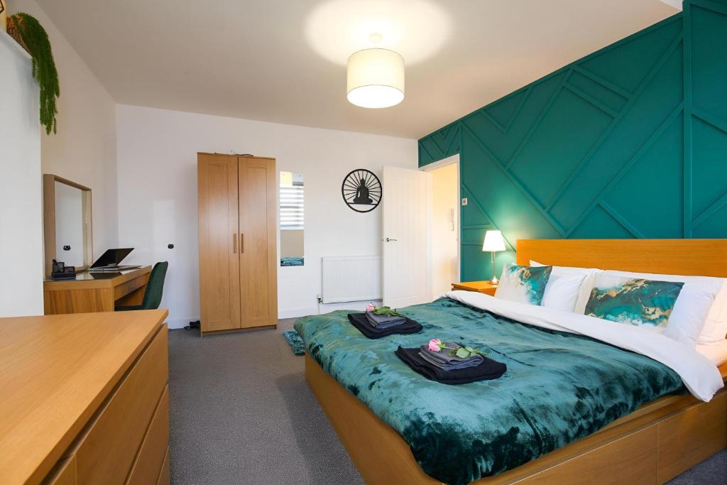 a bedroom with a large bed with a green headboard at Modern Spacious Apartment Steps from City Centre in Norwich